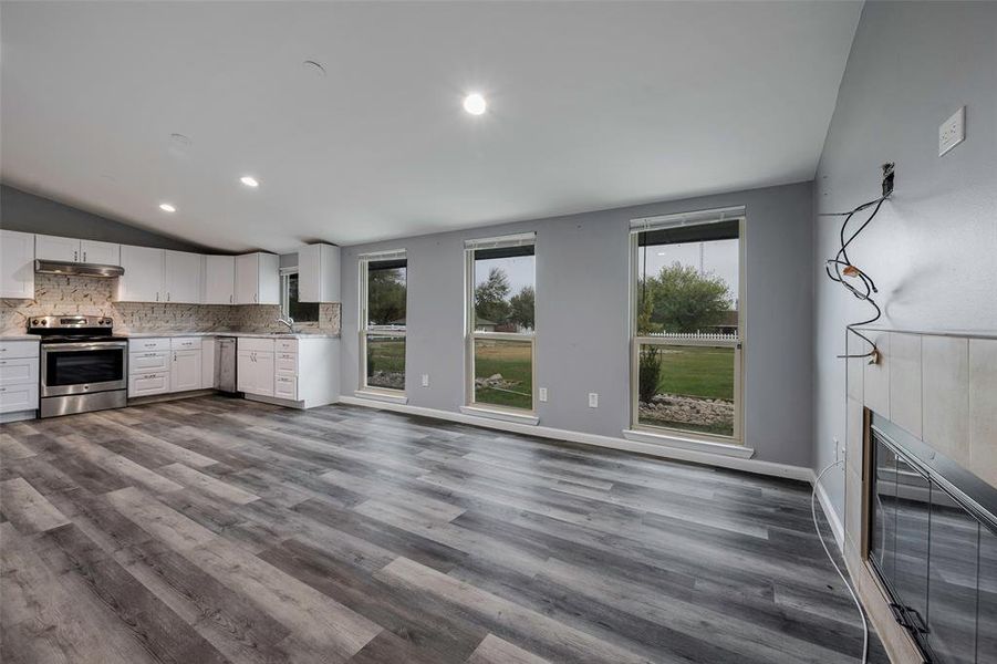 Kitchen with white cabinetry, appliances with stainless steel finishes, lofted ceiling, and hardwood / wood-style flooring