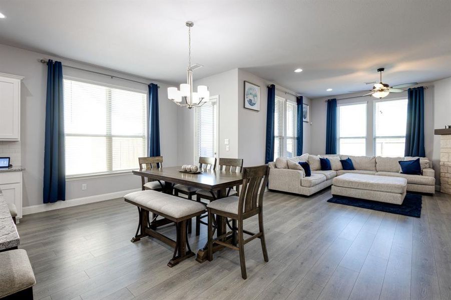 Dining room with hardwood / wood-style flooring, ceiling fan with notable chandelier, and a wealth of natural light