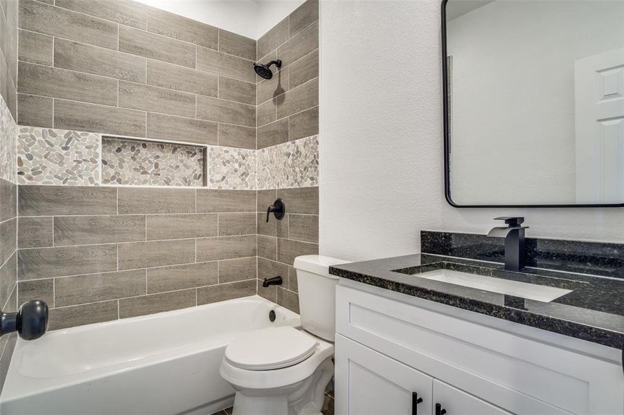 Full bathroom with tiled shower / bath, vanity, and toilet