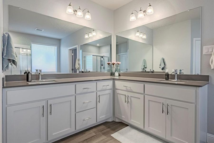 Primary Bathroom with a textured ceiling, wood-type flooring, vanity, and a shower with shower door