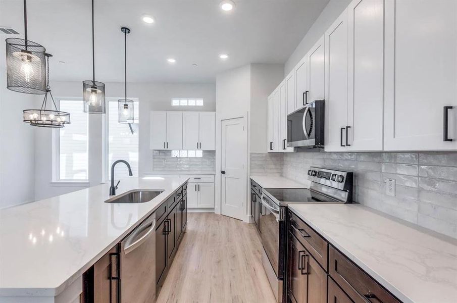 Kitchen with white cabinets, appliances with stainless steel finishes, plenty of natural light, and sink