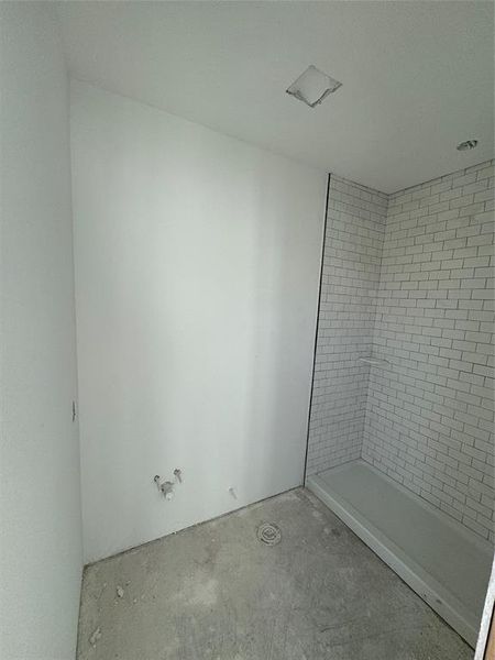 Bathroom featuring concrete flooring and a tile shower