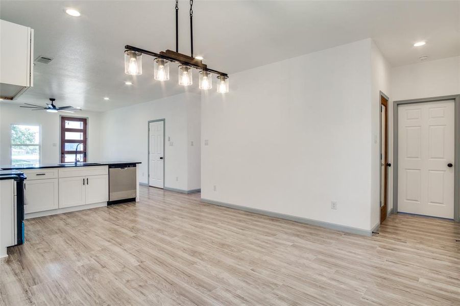 Kitchen with light wood-type flooring, white cabinetry, sink, and stainless steel dishwasher