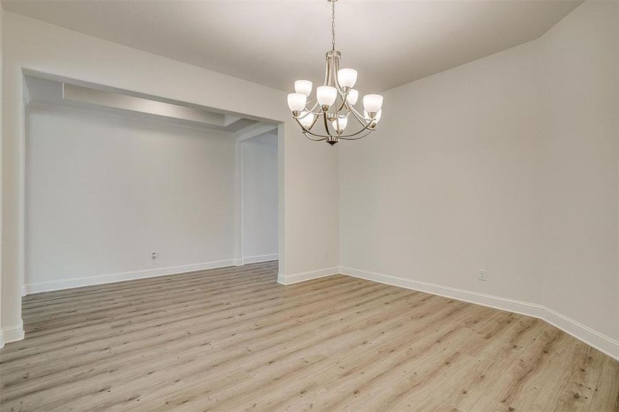 Unfurnished room with light hardwood / wood-style floors and a chandelier