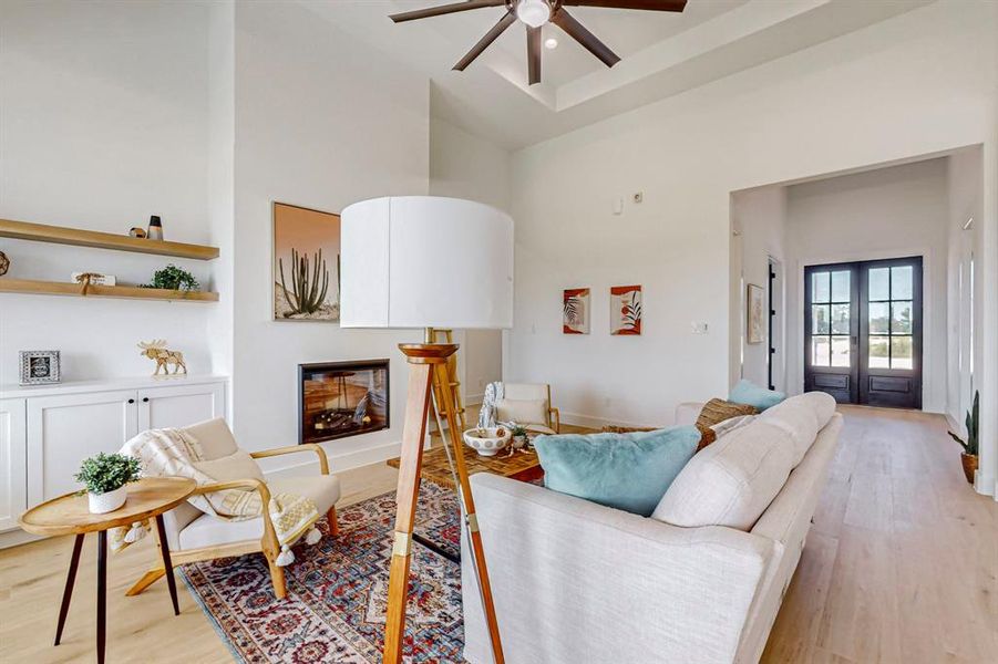 Living room with ceiling fan, french doors, a towering ceiling, and light hardwood / wood-style flooring