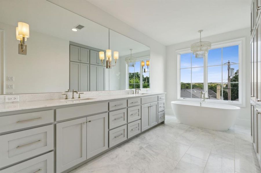 Primary bathroom featuring vanity, a notable chandelier, and a bath