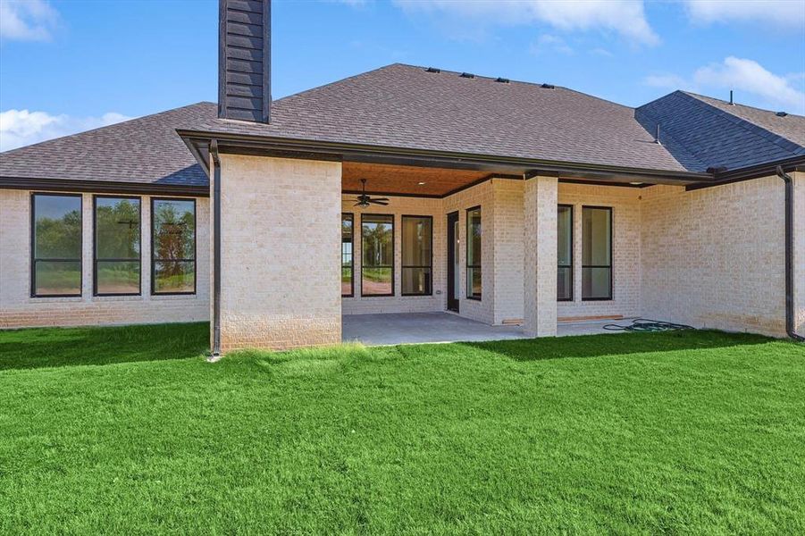 Rear view of house featuring a yard, ceiling fan, and a patio