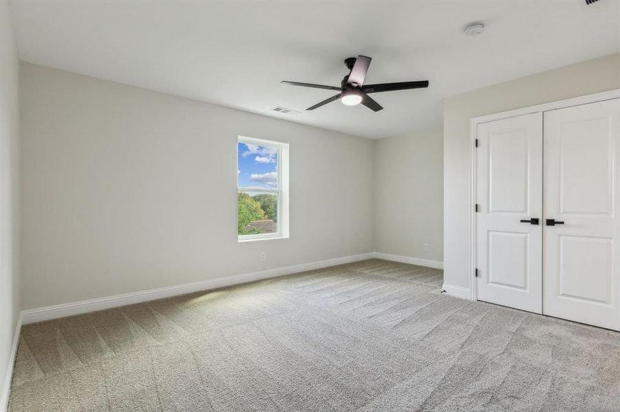 Unfurnished bedroom featuring ceiling fan, light colored carpet, and a closet