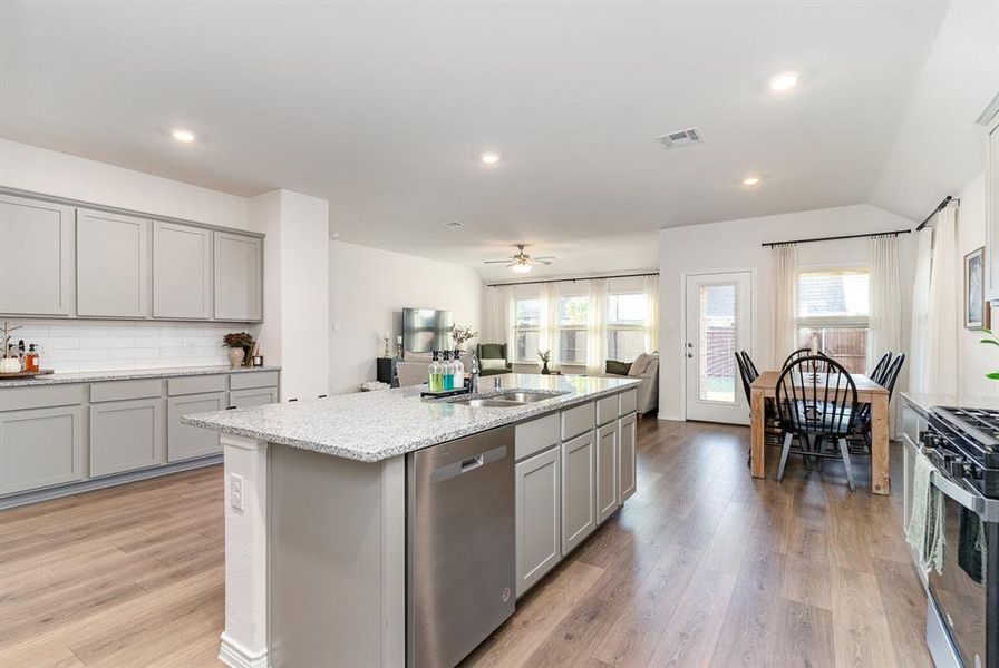 Kitchen featuring a center island with sink, sink, appliances with stainless steel finishes, and light hardwood / wood-style floors