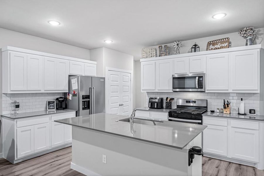 Kitchen featuring appliances with stainless steel finishes, sink, an island with sink, and light wood-type flooring