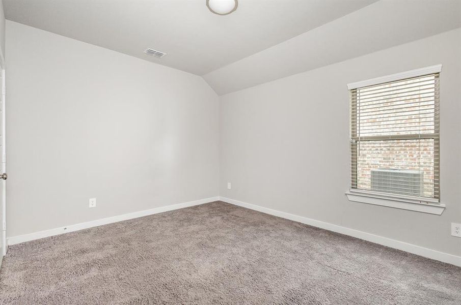 Carpeted empty room featuring lofted ceiling