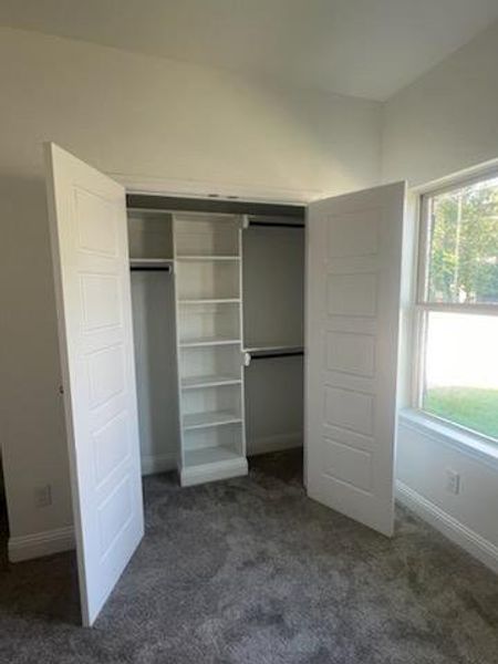 Unfurnished bedroom featuring dark carpet and a closet