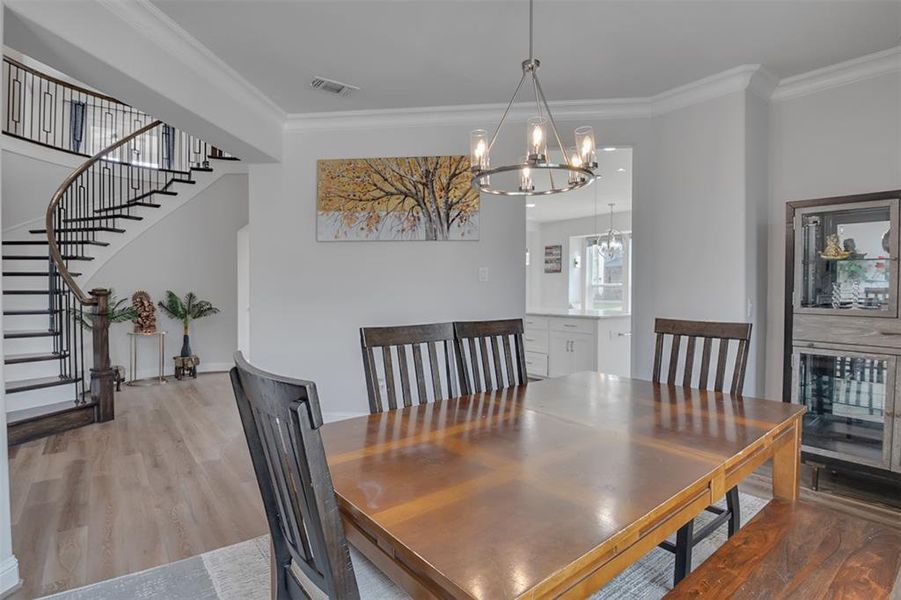 Dining area featuring ornamental molding, an inviting chandelier, and wood-type flooring
