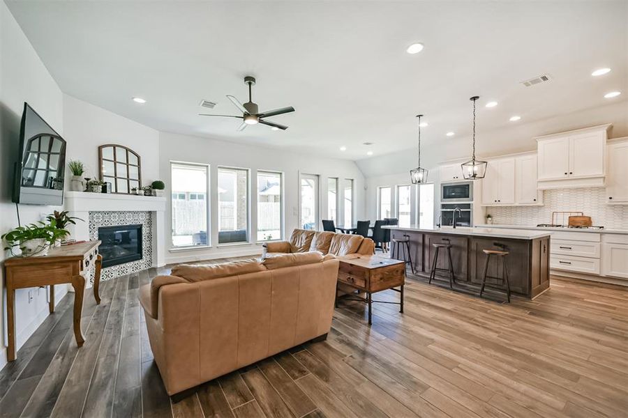 Living room features beautiful flooring, aceiling fan, high ceilings, and a wallof windows.