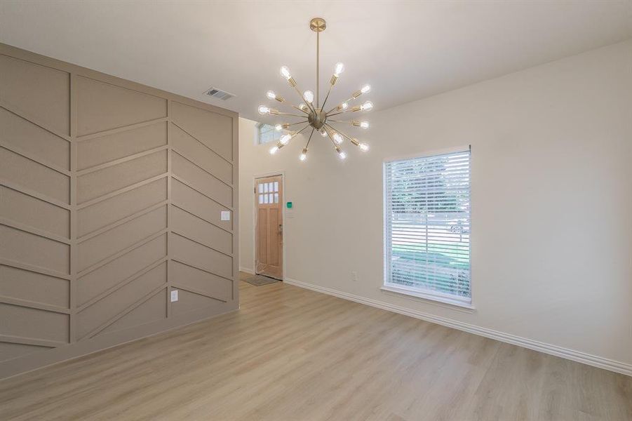 Unfurnished room featuring a chandelier and light wood-type flooring