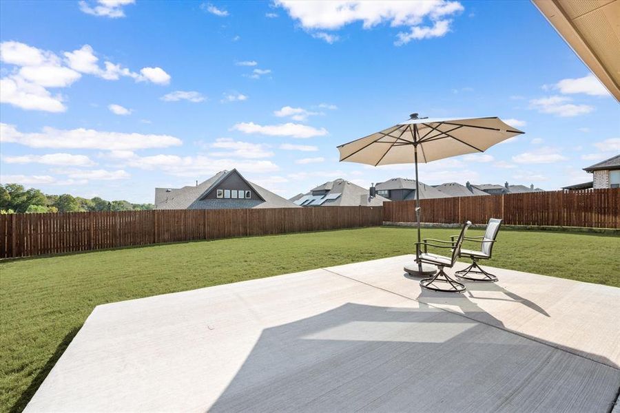 View from the extended patio in the backyard. 6 foot stained fence encloses the large backyard.