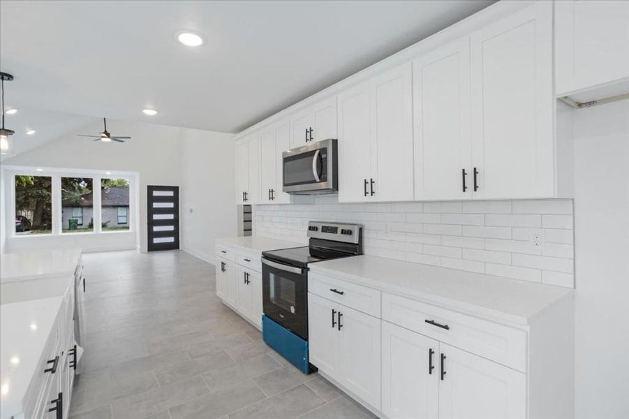 Kitchen featuring appliances with stainless steel finishes, decorative backsplash, white cabinetry, and ceiling fan