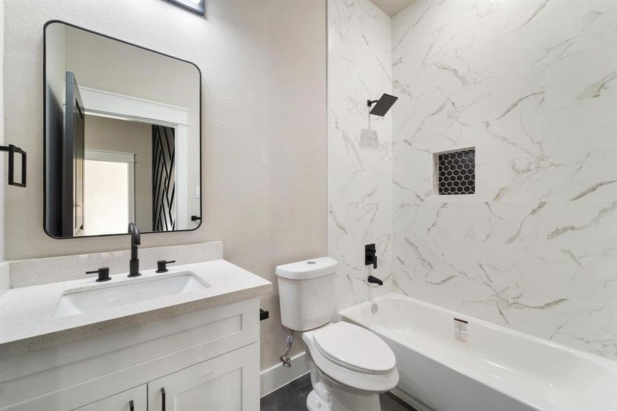 This complete bathroom offers a shower-tub combo, a convenient soap niche, and a charming vanity adorned with silestone countertops.