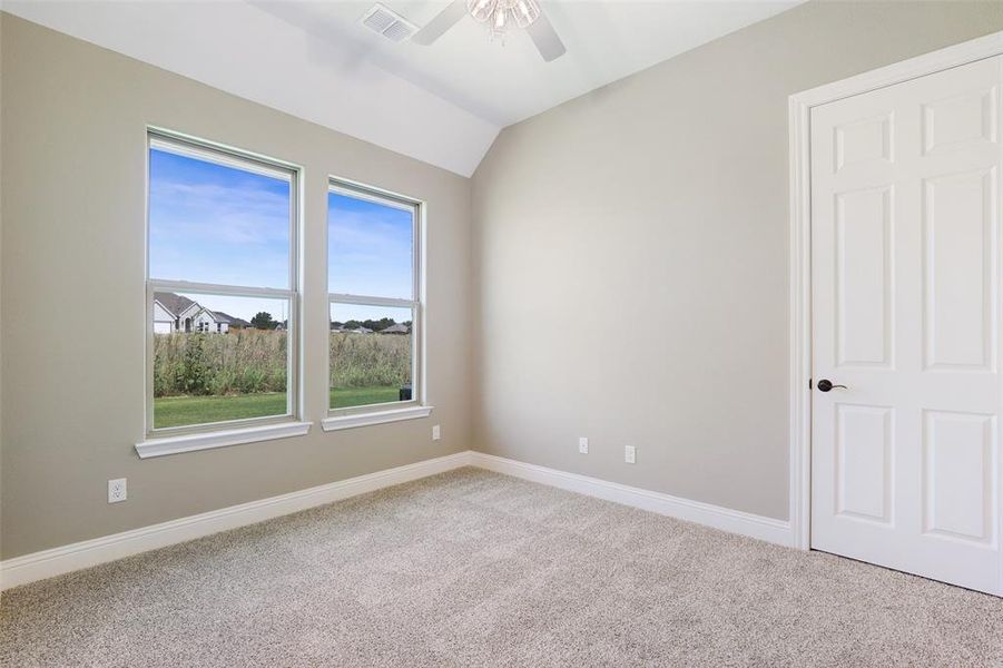 Carpeted spare room with ceiling fan and lofted ceiling