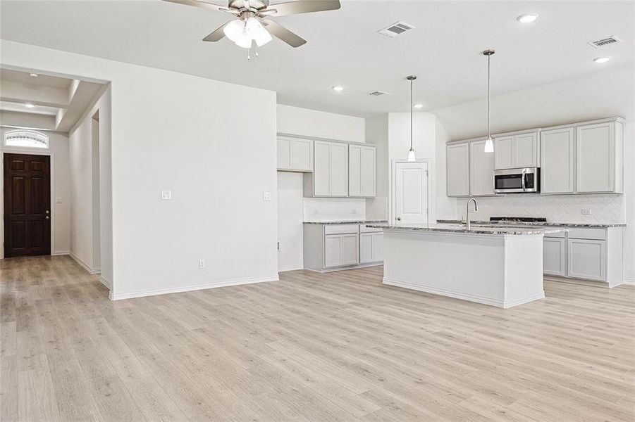 Kitchen featuring ceiling fan, light hardwood / wood-style flooring, and a kitchen island with sink