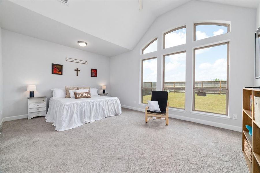 This is a spacious and well-lit Primary bedroom featuring high ceilings with large windows that allow for ample natural light, creating a comfortable and serene living space.