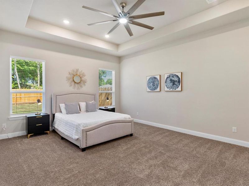 Carpeted bedroom with ceiling fan and a tray ceiling