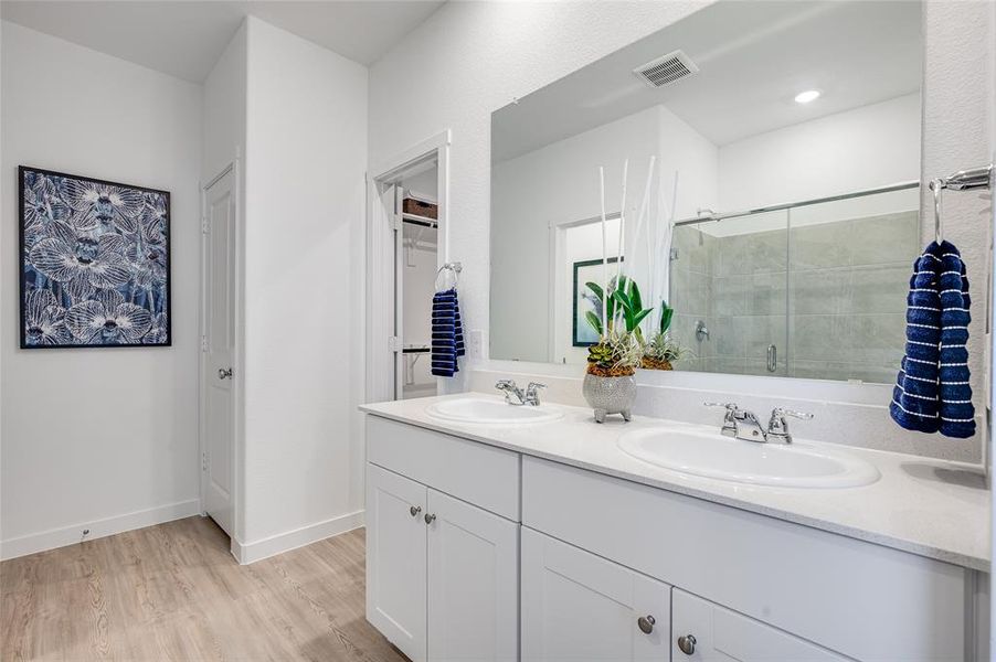 Bathroom with a shower with door, hardwood / wood-style floors, and double vanity