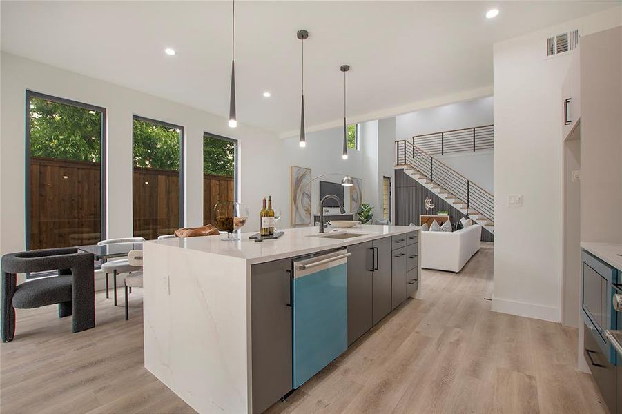 Kitchen with a kitchen island with sink, decorative light fixtures, sink, stainless steel dishwasher, and light hardwood / wood-style floors