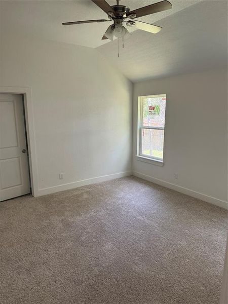 Primary Bedroom with carpet flooring, ceiling fan, and vaulted ceiling