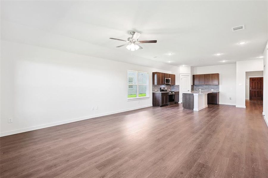 Unfurnished living room with sink, ceiling fan, and dark hardwood / wood-style floors