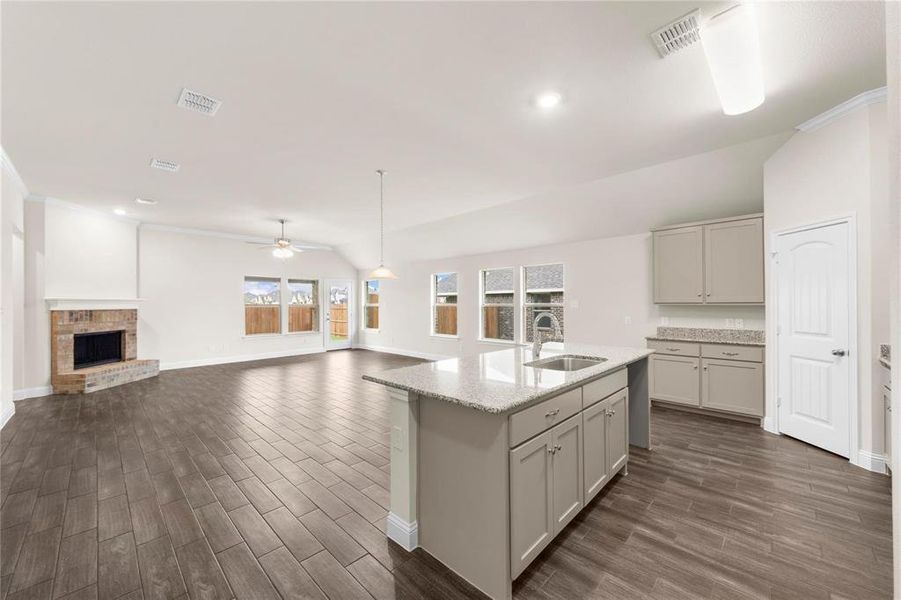 Kitchen featuring sink, a brick fireplace, gray cabinets, vaulted ceiling, and dark hardwood / wood-style flooring