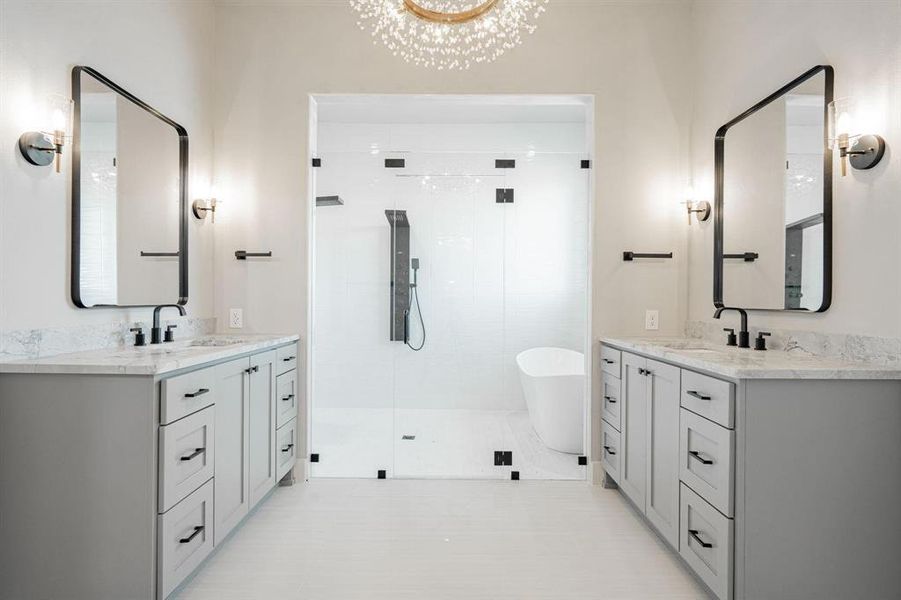 Example of builders Bathroom w tile patterned floors, dual vanity, shower and bath, and a decorative chandelier