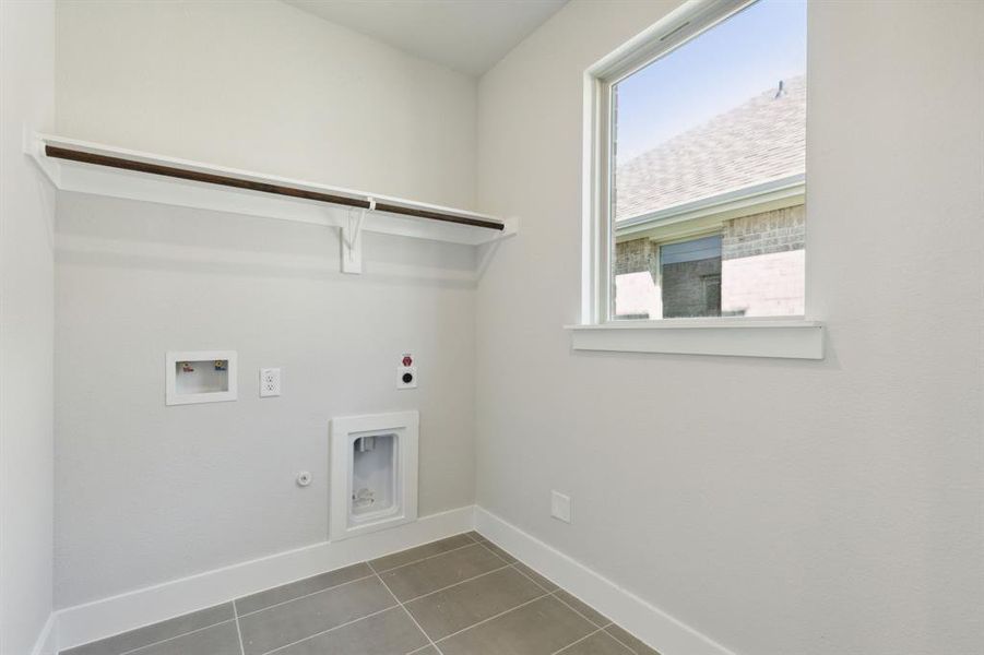 Laundry area with hookup for a washing machine, gas dryer hookup, dark tile patterned floors, and electric dryer hookup