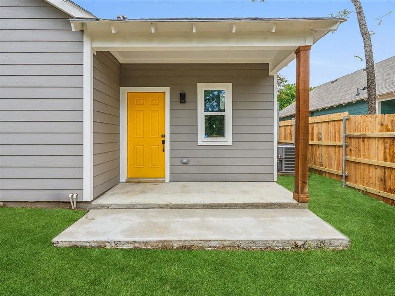 View of exterior entry featuring central AC unit and a yard