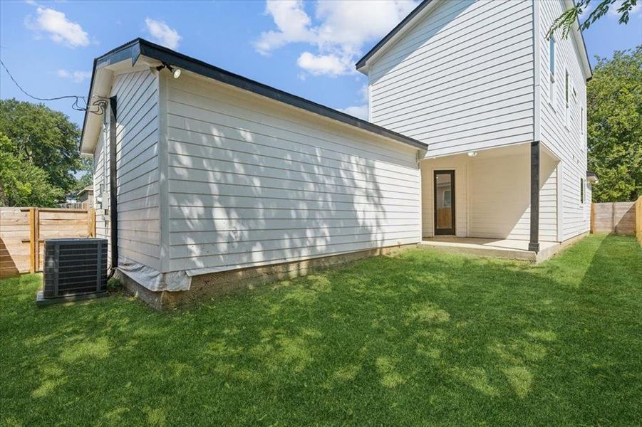 Back of house with a yard and central AC