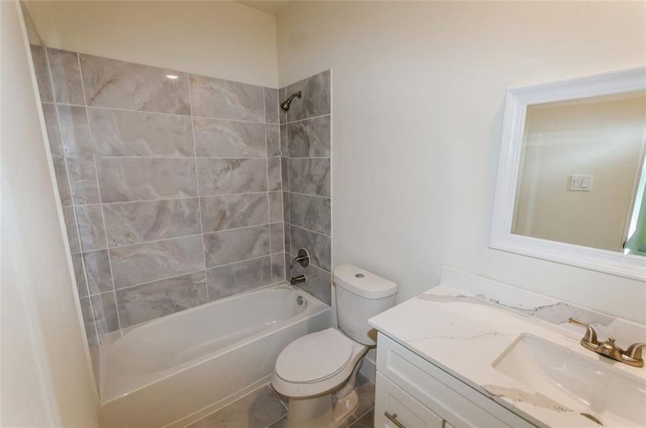 Full bathroom with tile floors, vanity, toilet, and tiled shower / bath combo