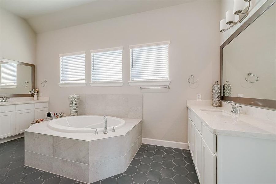 The primary bathroom has a vanity area and separate tub with tile surround.