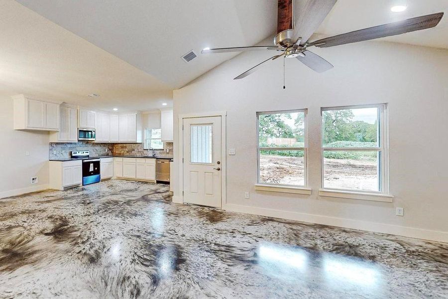 Unfurnished living room featuring beamed ceiling, high vaulted ceiling, ceiling fan, and sink