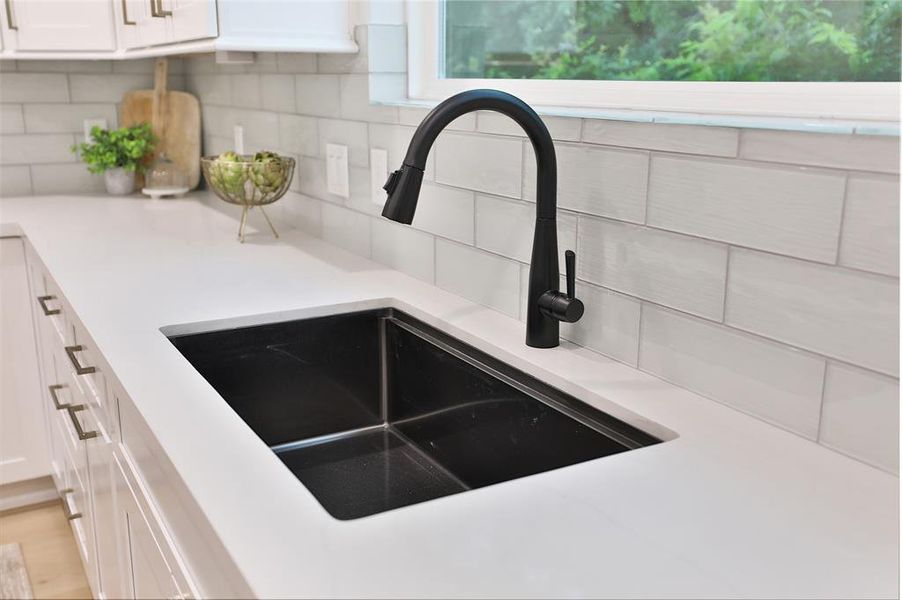 Black stainless under mount sink is surrounded with ice look 3x9 classic subway tiles.