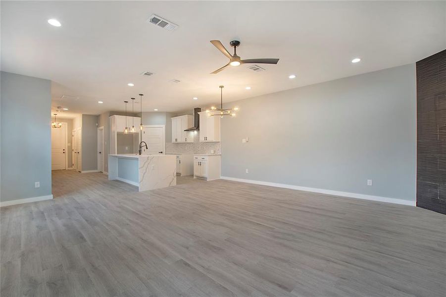 Unfurnished living room with ceiling fan, sink, and light hardwood / wood-style flooring