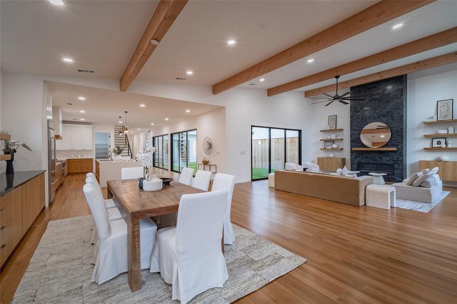 Dining space featuring a large fireplace, beam ceiling, and light wood-type flooring