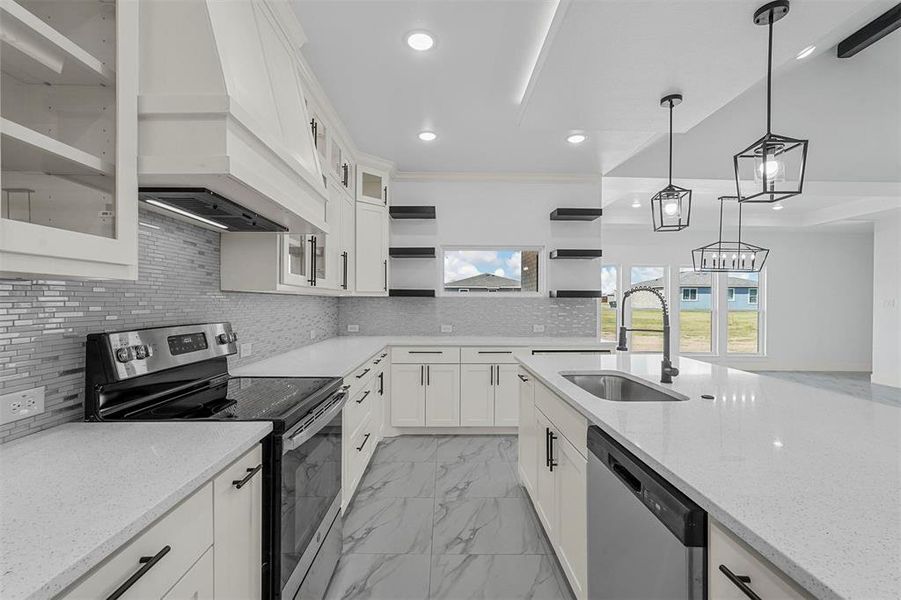 Kitchen featuring appliances with stainless steel finishes, hanging light fixtures, white cabinets, light stone countertops, and sink