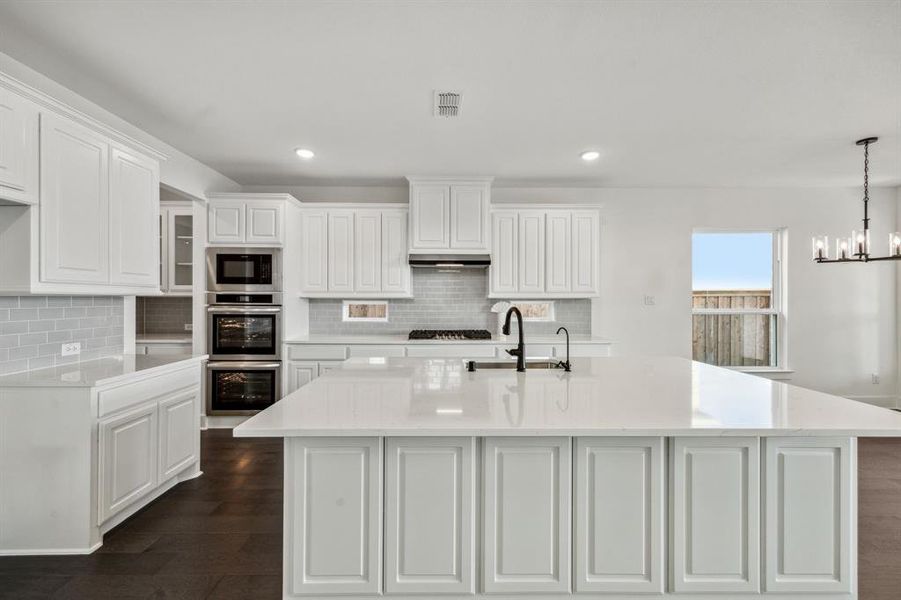 Kitchen featuring a notable chandelier, dark hardwood / wood-style flooring, white cabinetry, and a kitchen island with sink