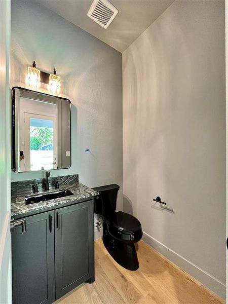 Bathroom featuring hardwood / wood-style flooring, toilet, and vanity