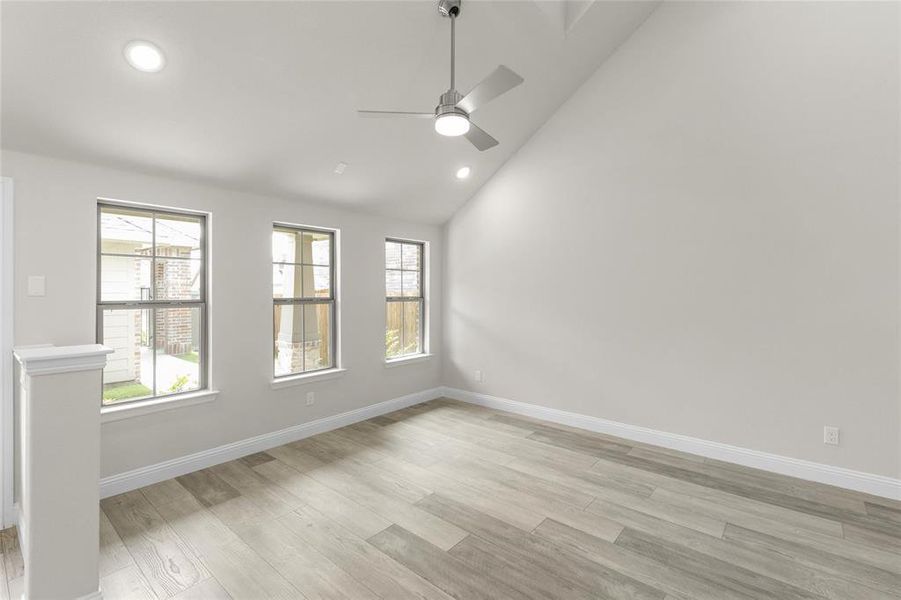 Spare room featuring ceiling fan, light wood-type flooring, and lofted ceiling