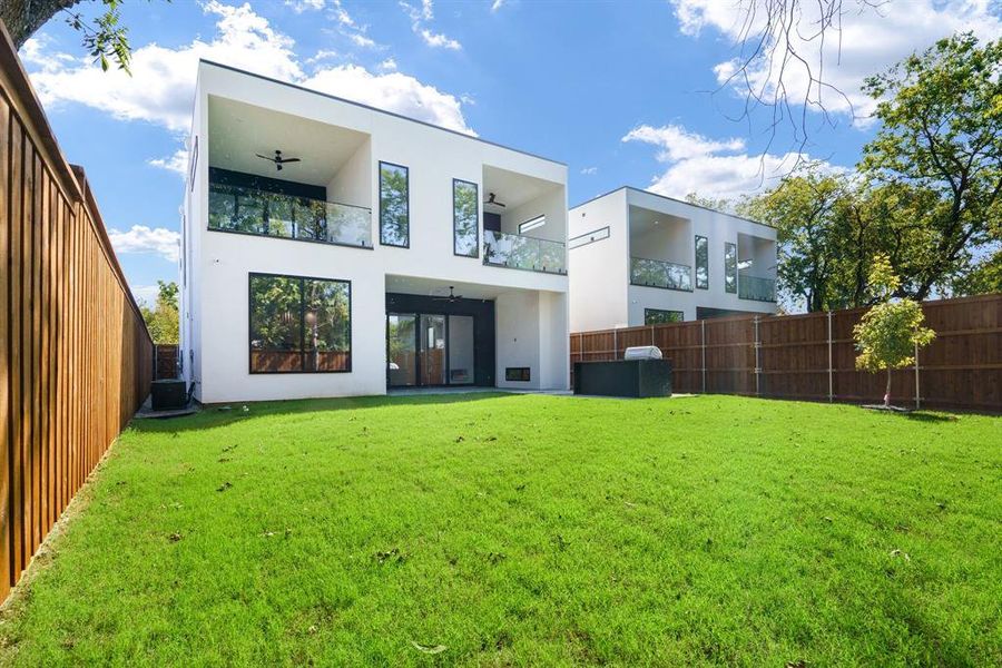 Rear view of house featuring a balcony and a lawn