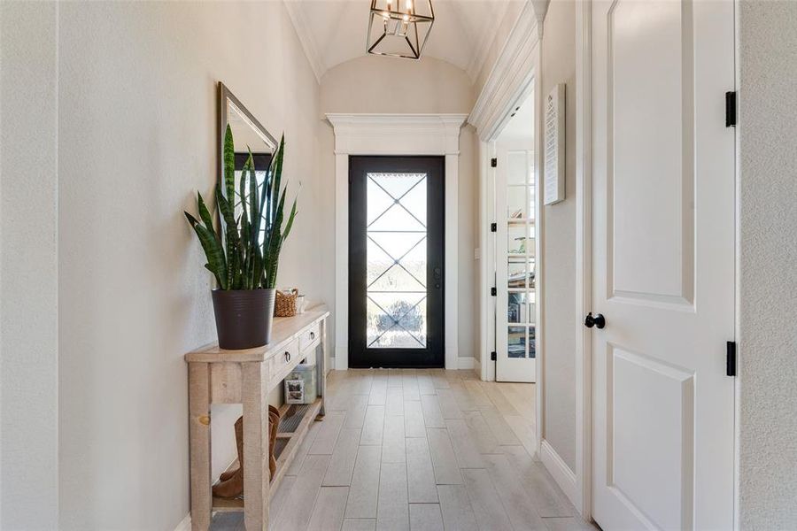 Foyer with light hardwood / wood-style floors, lofted ceiling, and an inviting chandelier