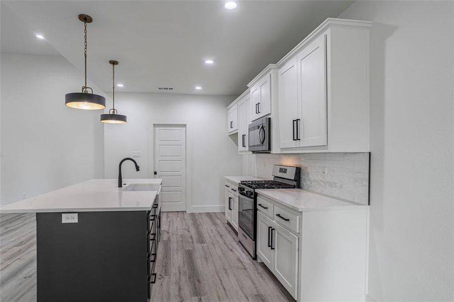 Kitchen featuring light hardwood / wood-style flooring, tasteful backsplash, an island with sink, appliances with stainless steel finishes, and sink