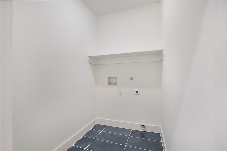 Washroom with gas dryer hookup, washer hookup, dark tile patterned floors, and hookup for an electric dryer