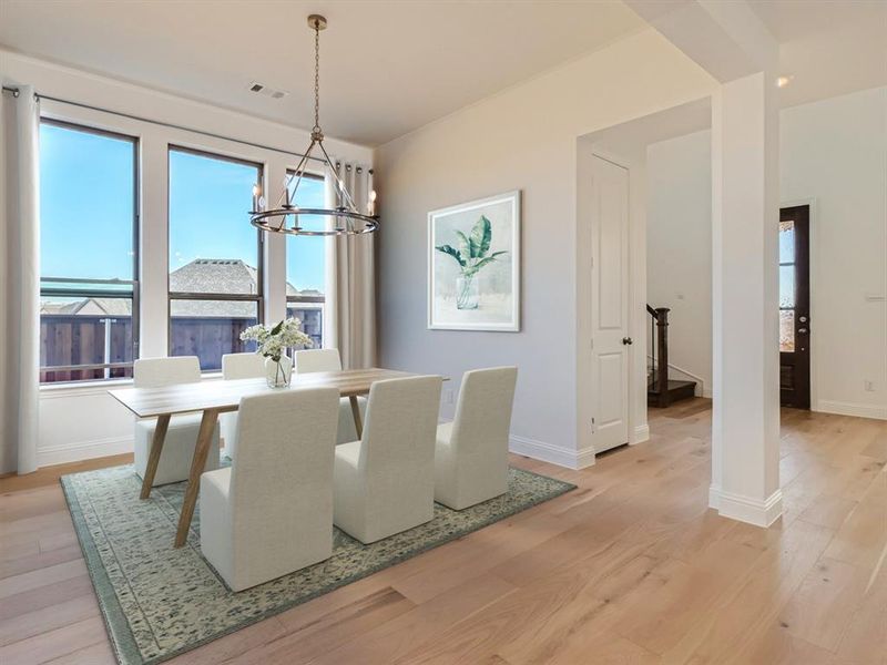 Virtually staged photo - Dining room featuring light hardwood / wood-style floors and a notable chandelier